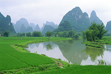 Reflections in water and the distinctive karst limestone landscape typical of the region south of Guilin, Guangxi, Yangshuo, China, Asia