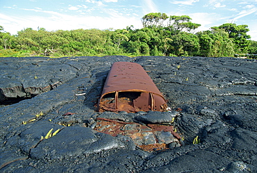 School bus near Kaimu buried in the 1988 basalt lava flows that covered a large area of the south east Puna coast and cut highway 130, Big Island, Hawaii, United States of America, North America