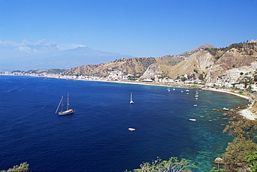 View across bay south of Taormina to the east coast resort of Giardina-Naxos, and Mount Etna erupting in distance, island of Sicily, Italy, Mediterranean, Europe