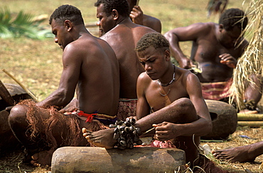 Tamtam drummer from the Island of Pentecost attaching a nut rattle to his ankle for a traditional dance at a cultural festival, Port Vila, Efate Island, Vanuatu