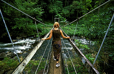 Hiker crossing a river on the Lavena Coastal Walk in this famous national park on the south coast of Taveuni - the 'Garden Island', Bouma National Park, Taveuni, Fiji