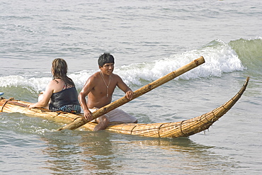 Tourist girl on a 'caballito (little horse) de totora' reed boat at the popular far north coast fishing & surfing village of Huanchaco, near Trujillo, Peru, South America.