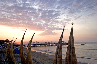 Sunset behind 'caballitos (little horses) de totora' reed boats at the popular far north coast fishing & surfing village of Huanchaco, near Trujillo, Peru, South America.