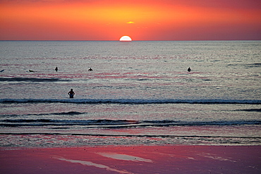 Surfers and swimmers at sunset off Playa Guiones beach, Nosara, Nicoya Peninsula, Guanacaste Province, Costa Rica, Central America