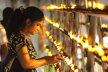 Devotee lighting candles at sunset in the Temple of the Sacred Tooth Relic (Temple of the Tooth), site of Buddhist pilgrimage, Kandy, Sri Lanka, Asia