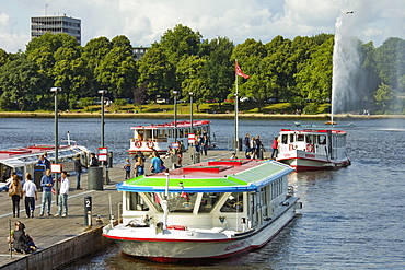 Tour boats that ply Alster Lake moored at the Jungfernstieg with the Lombardsbruecke beyond, Hamburg, Germany, Europe