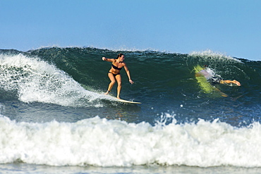 Girl surfer riding wave at popular Playa Guiones surf beach, Nosara, Nicoya Peninsula, Guanacaste Province, Costa Rica, Central America