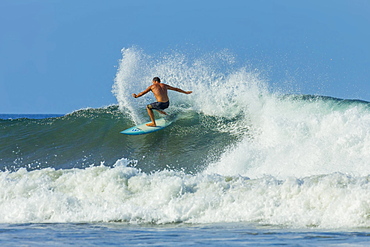 Surfer on shortboard riding wave at popular Playa Guiones surf beach, Nosara, Nicoya Peninsula, Guanacaste Province, Costa Rica, Central America