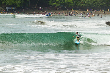 Surfer on a wave at this popular point break surf spot and small resort, Batu Karas, near Pangandaran, West Java, Java, Indonesia, Southeast Asia, Asia