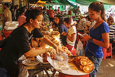 Girl wearing headphones buys food in the eating area of this huge old market, Central Market, city centre, Phnom Penh, Cambodia, Indochina, Southeast Asia, Asia