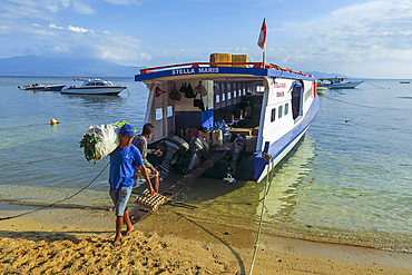 Men unload cargo from ferry at this coral fringed holiday island and scuba diving destination. Bunaken, North Sulawesi, Indonesia, Southeast Asia, Asia