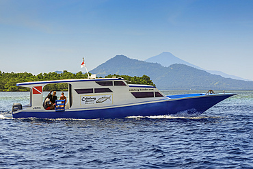 Dive boat with mainland and Manadotua Island beyond, off this coral fringed holiday and scuba island. Bunaken, North Sulawesi, Indonesia, Southeast Asia, Asia