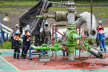 Workers in hard hats by steam pipes and valves at a volcanic facility run by Pertamina Geothermal Energy near Tomohon city, Lake Linow, Tomohon, North Sulawesi, Indonesia, Southeast Asia, Asia