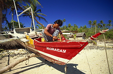 Man painting outrigger boat on Boracay island, off Panay, Philippines, Southeast Asia, Asia