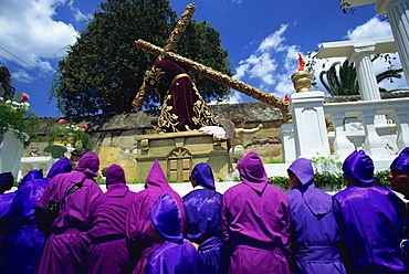 Men in purple robes carrying huge float on one of the famous Easter processions, Antigua, Guatemala, Central America