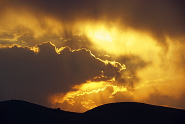 Sun behind dark clouds at sunset over hills at Guanajuato, central Mexico, North America