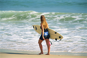 Girl carrying surfboard on beach, Byron Bay, New South Wales, Australia, Pacific