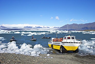 Amphibious boat and icebergs on glacial lake at Jokulsarlon with snow on the massive icecap of Vatnajokull behind, Iceland, Polar Regions