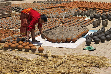 Woman turning pots to dry in sunshine, Potter's Square, Bhaktapur, Nepal, Asia