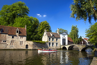 Tourist boat, at the Minnewater Lake and Begijnhof Bridge with entrance to Beguinage, Bruges, Belgium, Europe