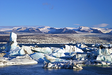 Icebergs on glacial lake at Jokulsarlon with snow on the massive icecap of Vatnajokull behind, Iceland, Polar Regions