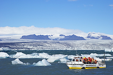 Amphibious vehicle between icebergs on glacial lake at Jokulsarlon with snow on massive icecap of Vatnajokull behind, Iceland, Polar Regions