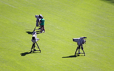 Camera operator standing on the lawn in a stadium at a sporting event