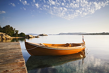 Boat being reflected in the water at dawn, Sardinia, Italy, Europe