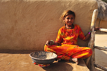 Young girl with a bowl for collecting camel dung, Thar Desert, Rajasthan, North India, India, Asia