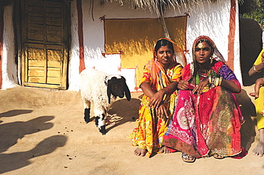 Women in colorful saris in front of a traditionally painted houses, Thar Desert, Rajasthan, North India, India, Asia