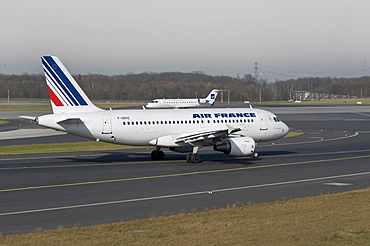 Air France Airbus A319-111 passenger jet on the runway of Duesseldorf International Airport, behind, a SAS Jet taking-off, North Rhine-Westphalia, Germany, Europe