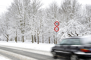 Car on a snow-covered road in winter, slip hazard, warning sign, prohibition sign, blur