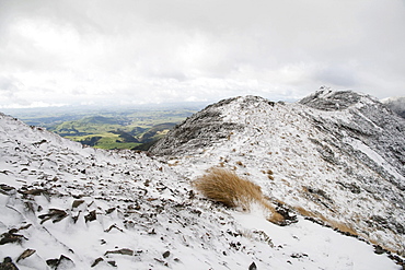 Snow-covered mountain crest and a green valley in the distance, near Sunrise Hut and Armstrong Saddle, Eastern Ruahine Forest Park, Hawke's Bay, New Zealand