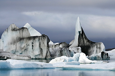 Floating icebergs, coloured with black lava ash, in the Joekulsarlon glacier lagoon of the Vatnajoekull Glacier, Iceland, Europe