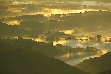 Fog in a hilly landscape with Schloss Herberstein castle in the early morning light, Kulm bei Weiz, Styria, Austria, Europe