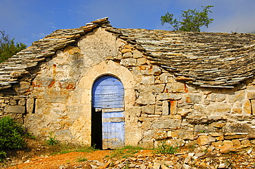 Blue wooden door, abandoned half-subterranean wine cellar with natural stone roof in Entre-deux-Monts at Riviere-sur-Tarn, Aveyron, France, Europe