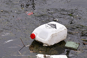 Dirty water, old canister with corrosive substances floating on dirty film