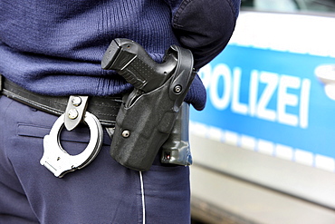 Police, police car, police officer with handcuffs and service weapon, Walther P99, in the holster