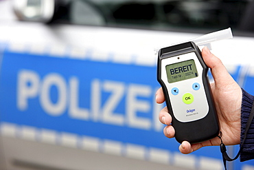 Police officer with breathalyser for checking the fitness to drive