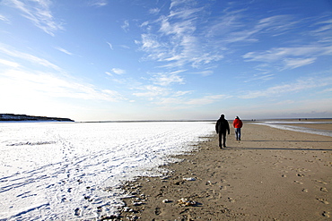 People walking along the snow-covered beach on the East Frisian North Sea island of Spiekeroog, Lower Saxony, Germany, Europe