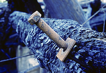 Thick iron bolt in a charred wooden beams, industrial ruin