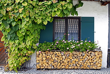 Traditional Bavarian building with stacked wood and flowers, Garmisch-Partenkirchen, Bavaria, Germany, Europe