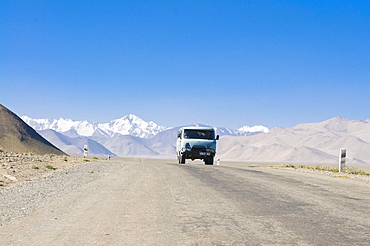 Country road leading to snow covered mountains, Karakul, Pamir Mountains, Tajikistan, Central Asia