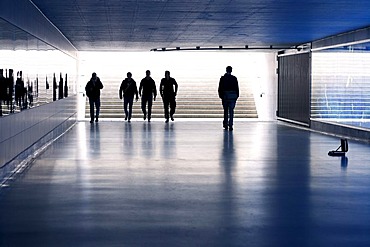 Man approaching a group of menacing-looking youths in a dark pedestrian underpass