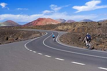 Cyclists on a road, volcanic landscape at Los Hervideros, Timanfaya National Park, Lanzarote, Canary Islands, Spain, Europe