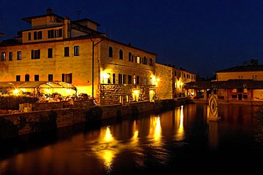 The basin of hot sulphur spring in Bagno Vignoni and Hotel Le Terme at night, Orcia Valley, Tuscany, Italy, Europe