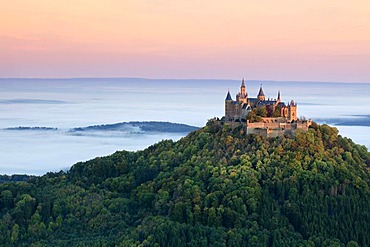 Burg Hohenzollern Castle in the morning light with autumn forests, early morning fog, Swabian Alb, Baden-Wuerttemberg, Germany, Europe