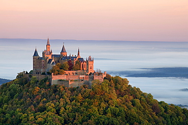 Burg Hohenzollern Castle in the morning light with autumn forests, early morning fog, Swabian Alb, Baden-Wuerttemberg, Germany, Europe