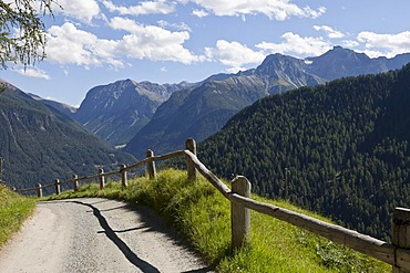 Mountains, meadows and a sunny trail in the Lower Engadine, Graubuenden or Grisons, Switzerland, Europe