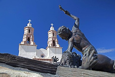 The Shrine of the Stations of the Cross, sculptures by artist Huberto Maestas, on a hill above town, the Chapel of All Saints at back, San Luis, Colorado, USA